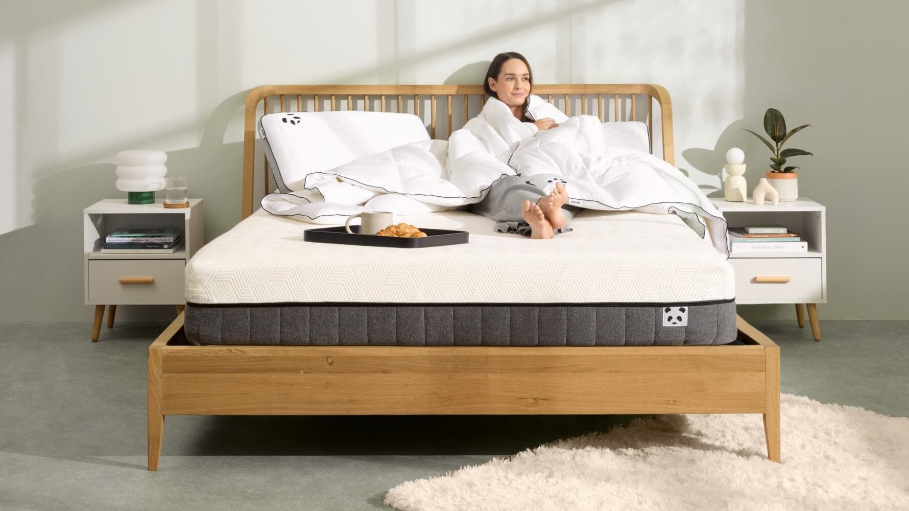 Woman relaxing on a new mattress in a cozy bedroom, showcasing comfort and style.