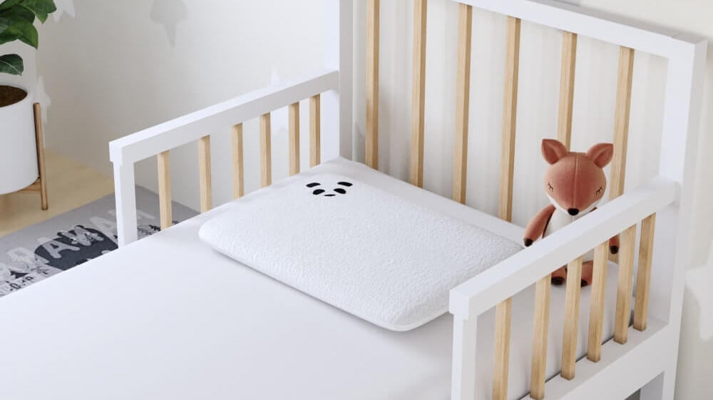 Cozy toddler bed with a soft pillow and a stuffed fox toy, perfect for children's comfort and safety.