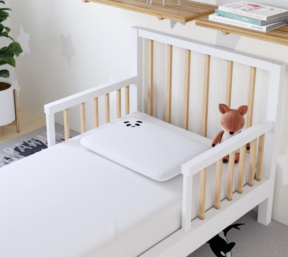 Cozy toddler bed with a soft pillow and a stuffed fox toy, perfect for children's comfort and safety.
