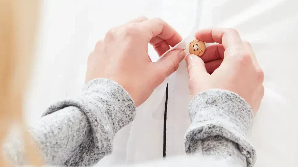 Close-up of a person sewing a button onto a duvet cover, showcasing DIY home decor skills.