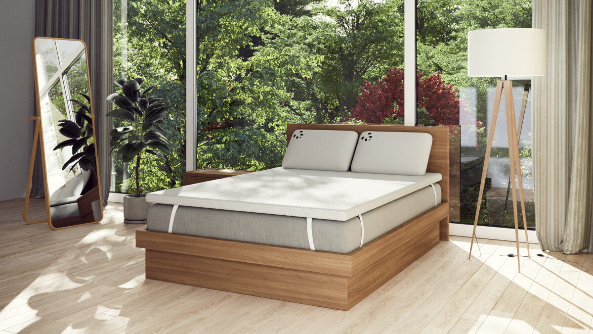 Modern bedroom with a wooden bed, mattress, and natural light from large windows.