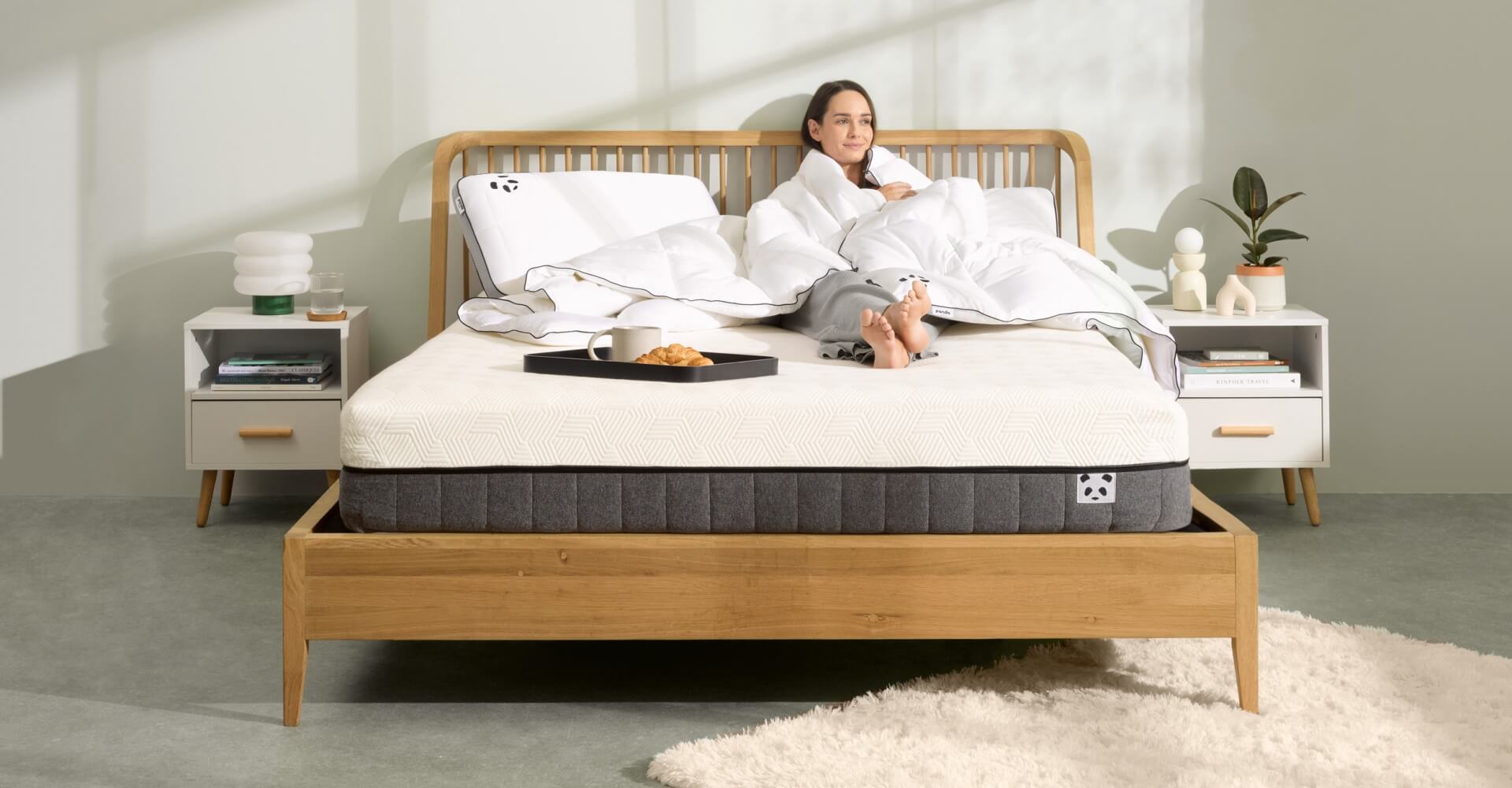 Woman relaxing on a new mattress in a cozy bedroom, showcasing comfort and style.