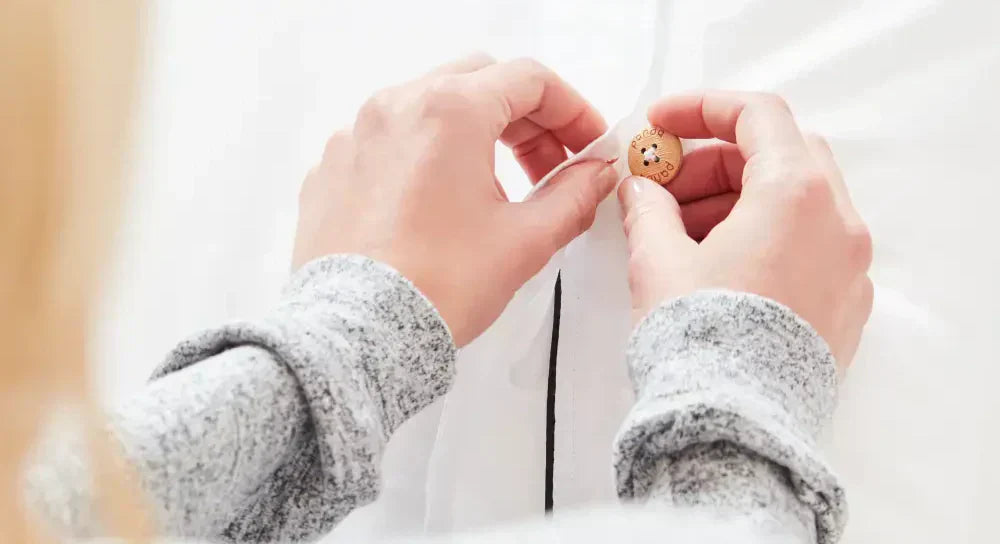 Close-up of a person sewing a button onto a duvet cover, showcasing DIY home decor skills.
