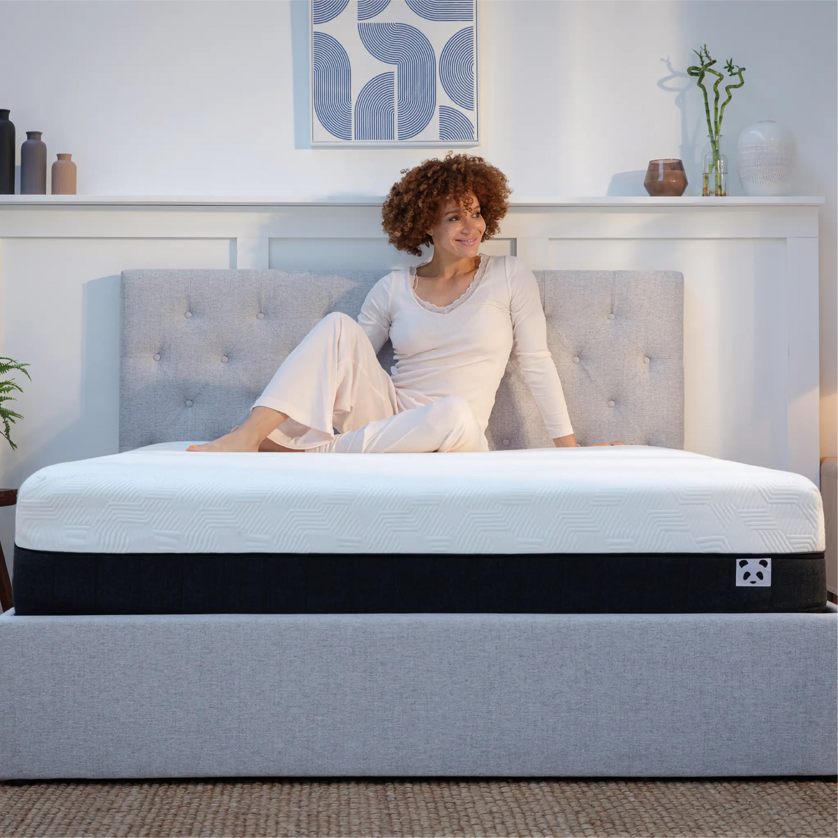 [HybridMattressPro] A woman in light pink pajamas sits on a Panda Bamboo mattress 