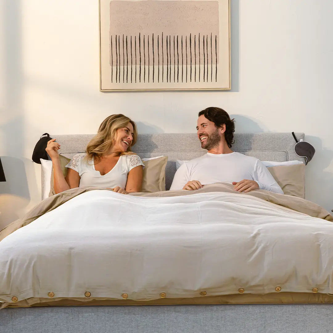 [Natural] couple smiling and laying on a bamboo and french linen bedding set